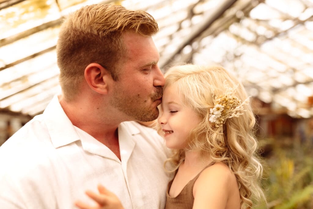 Father kissing his daughter during a natural family photography session in Kansas City