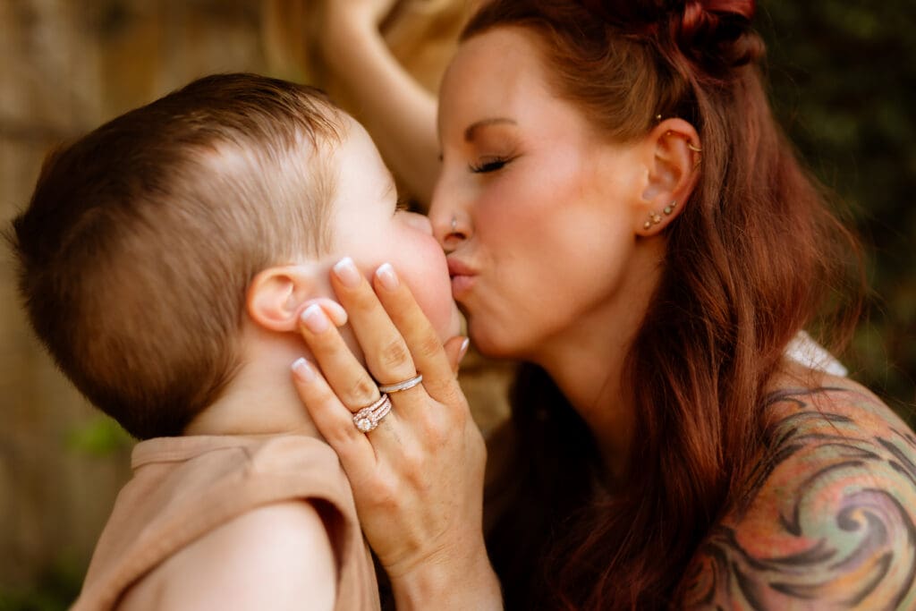 Mother holding her child close for a kiss during a natural light family session in Kanas City