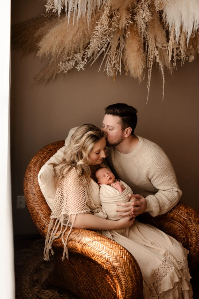 Studio newborn session near Smithville Missouri featuring a family posed naturally against a soft, neutral backdrop.