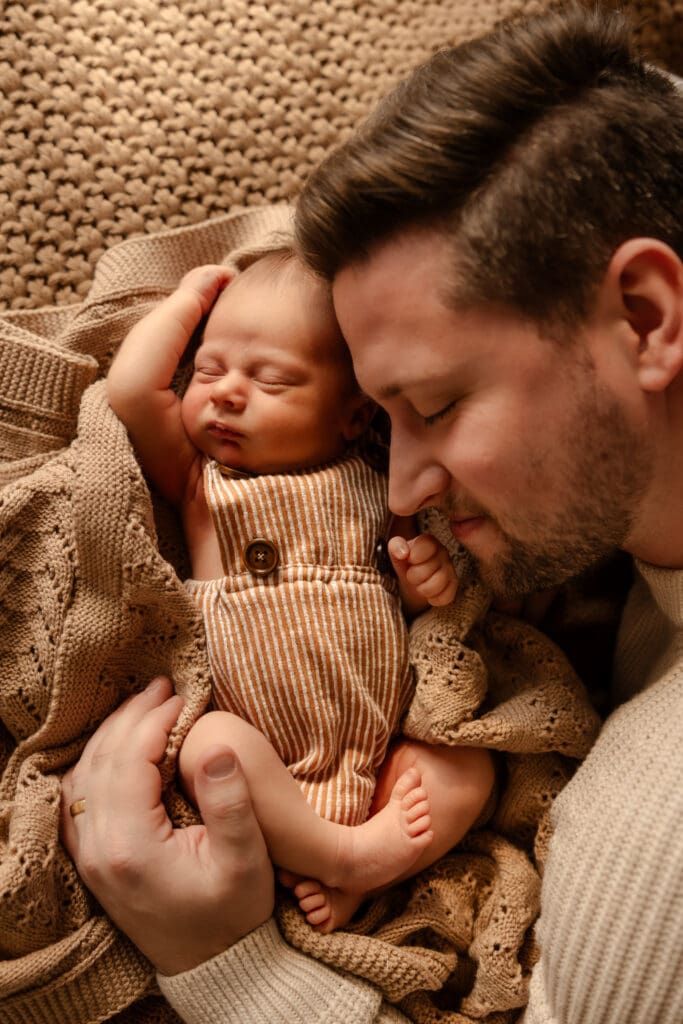 Kansas City newborn photographer capturing a father embracing his newborn baby during a calm and natural lifestyle session