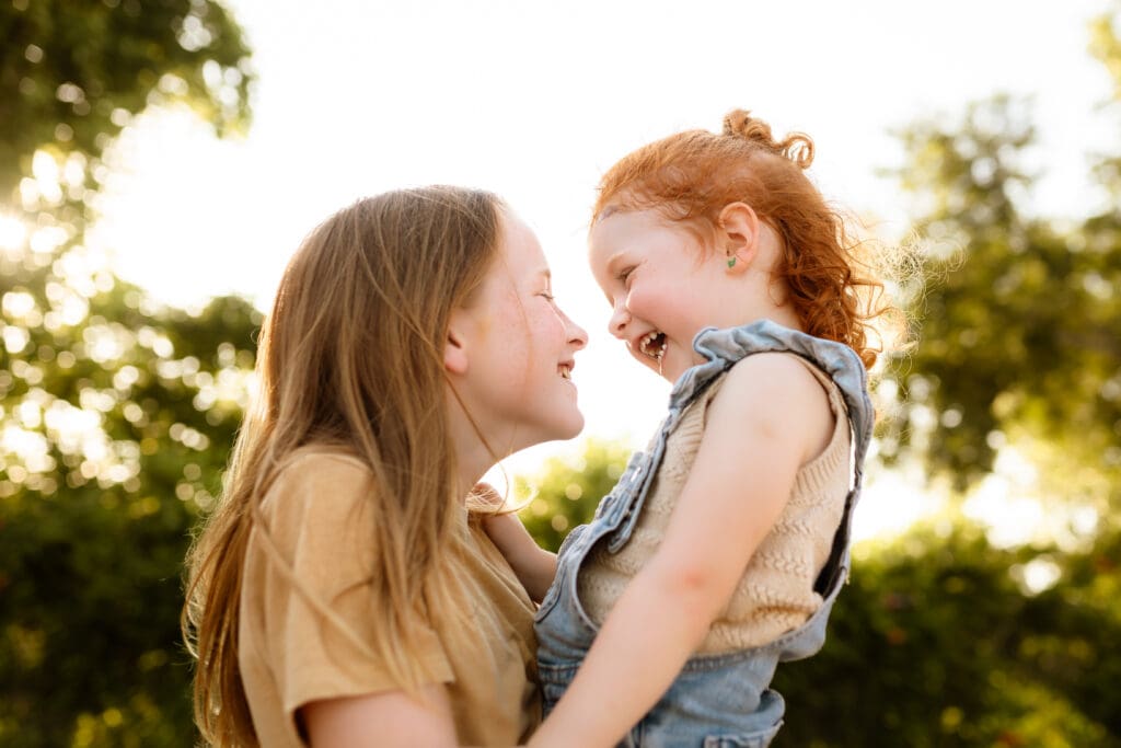 Siblings sharing a big giggle in a West Bottoms parking lot during an urban Kansas City family photo session