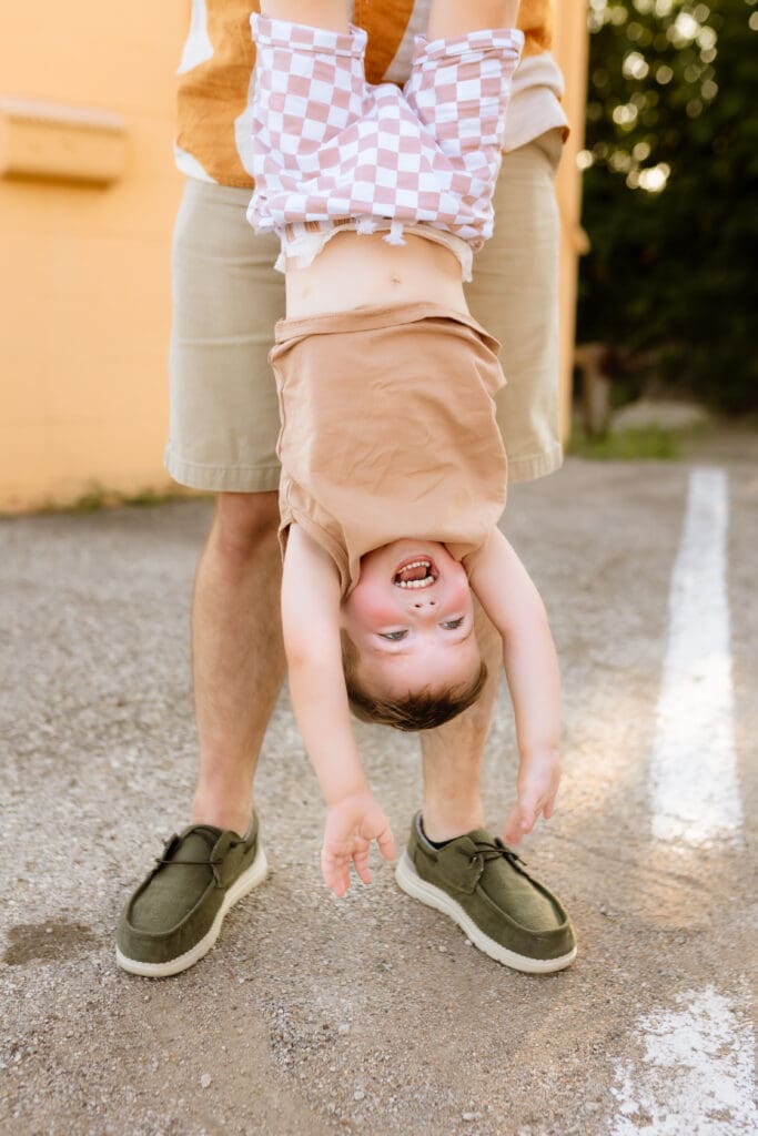 Little boy being playfully swung around with dad during an outdoor urban session near Kansas City Missouri